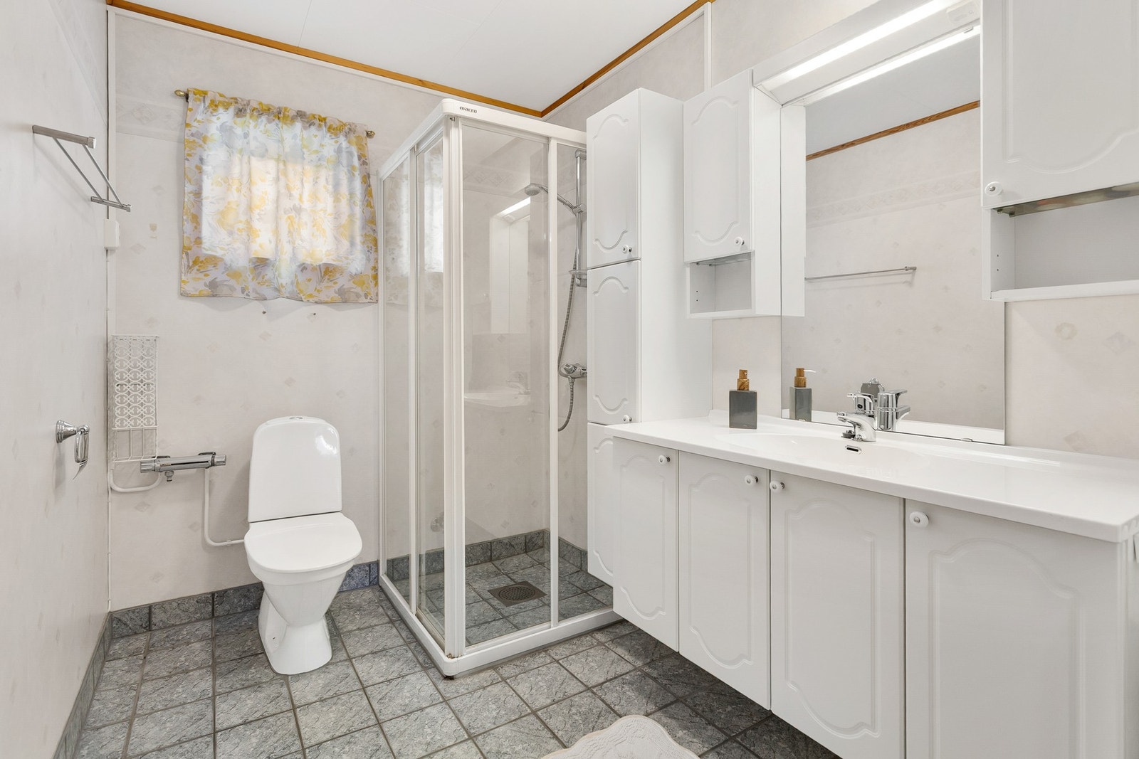 Badet er utstyrt med servantskap, dusjvegger, toalett og opplegg for vaskemaskin Galleribilde
