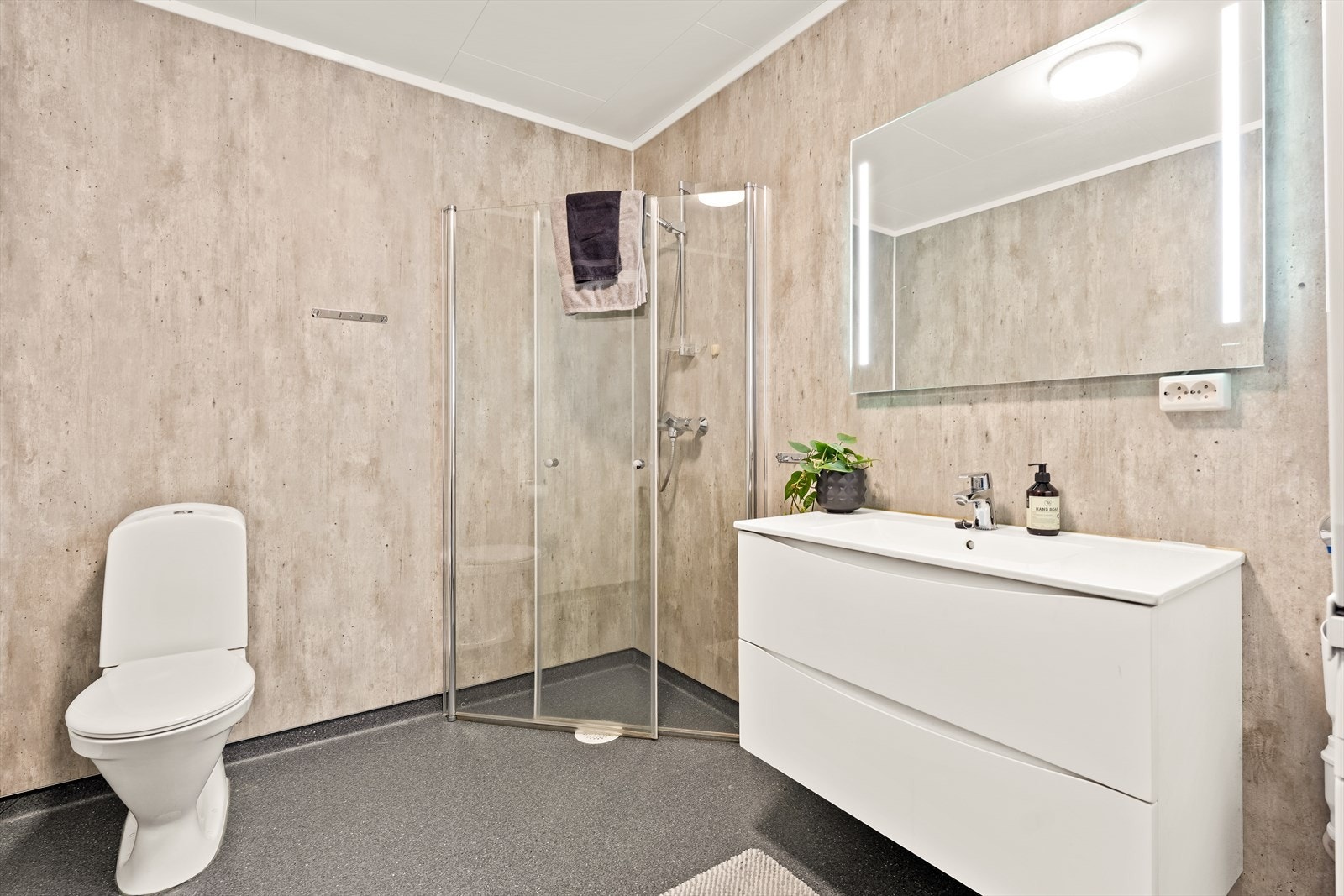 Pent bad med baderomsfliser på vegg og belegg på gulvet. Moderne innredning med glatte fronter. Galleribilde