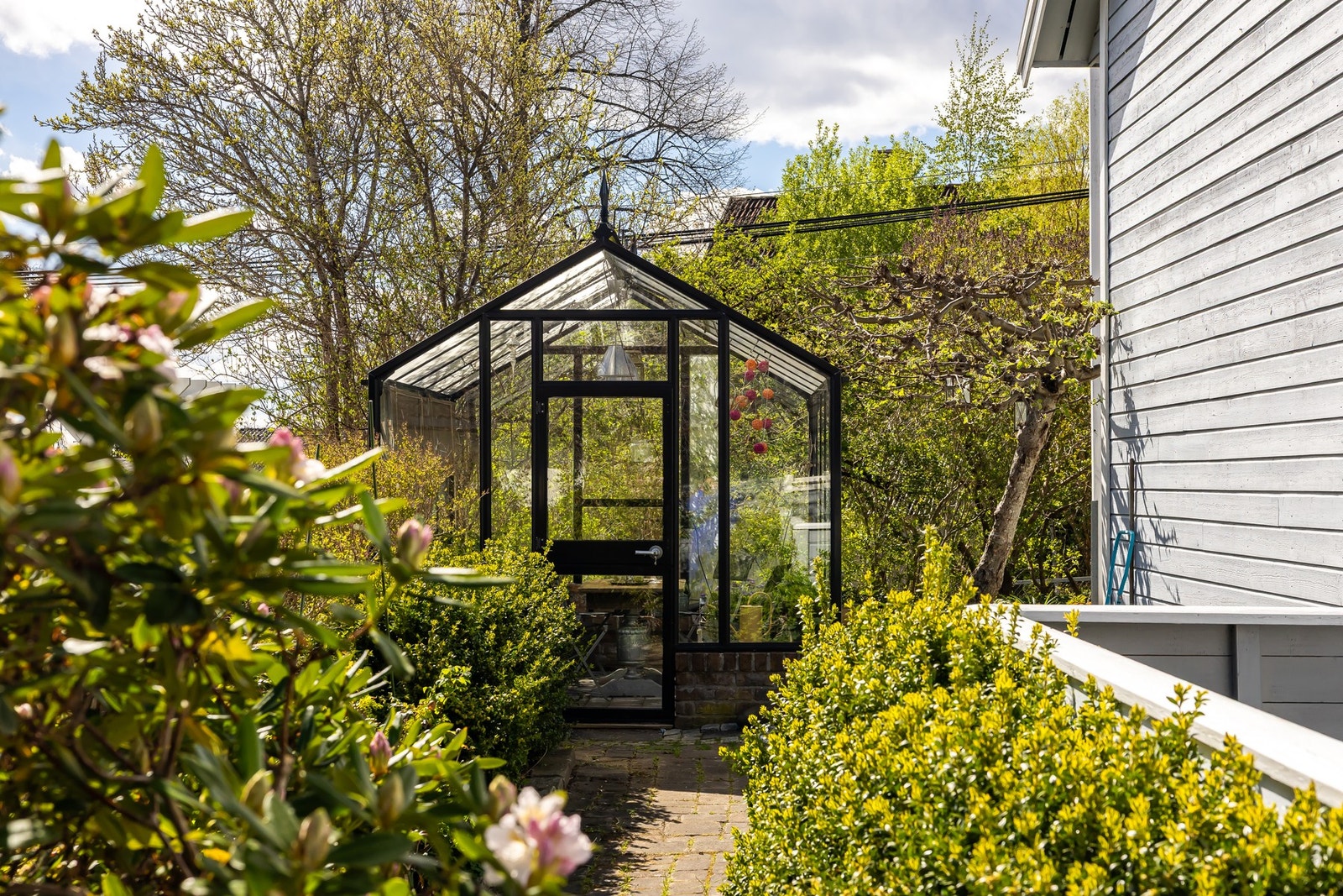 Det vakre drivhuset tilfører eiendommen ekstra sjarm og skaper en hyggelig ramme rundt hageopplevelsen. Galleribilde