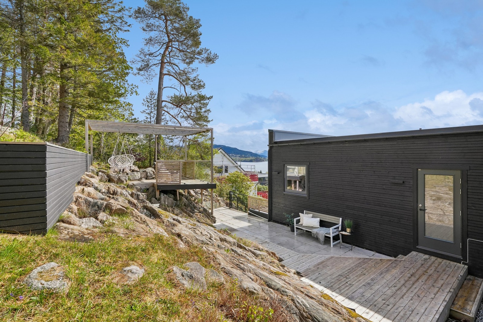På nordsiden av boligen er det opparbeidet et uteområde med terrassebord, betongheller og pergola i terrenget. Galleribilde
