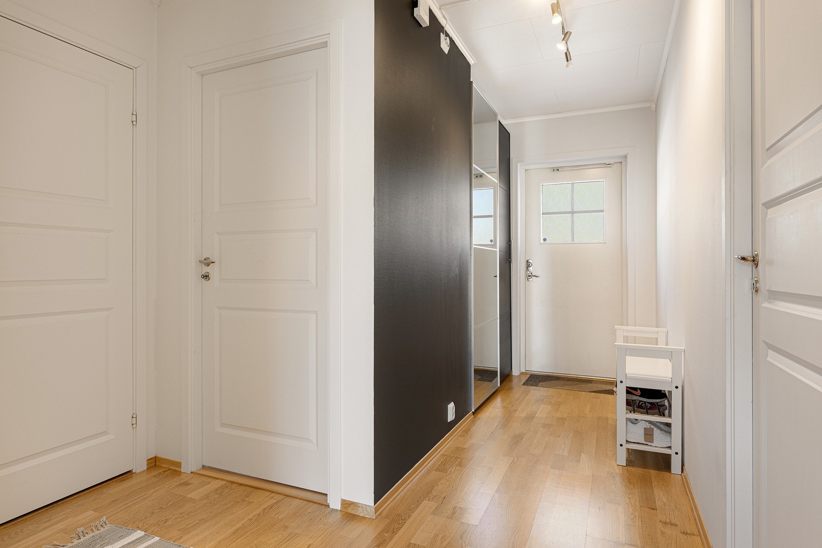 Entreen har lysmalte vegger og parkettgulv. Entreen har et garderobeskap for praktisk oppbevaring av yttertøy og vesker. Galleribilde