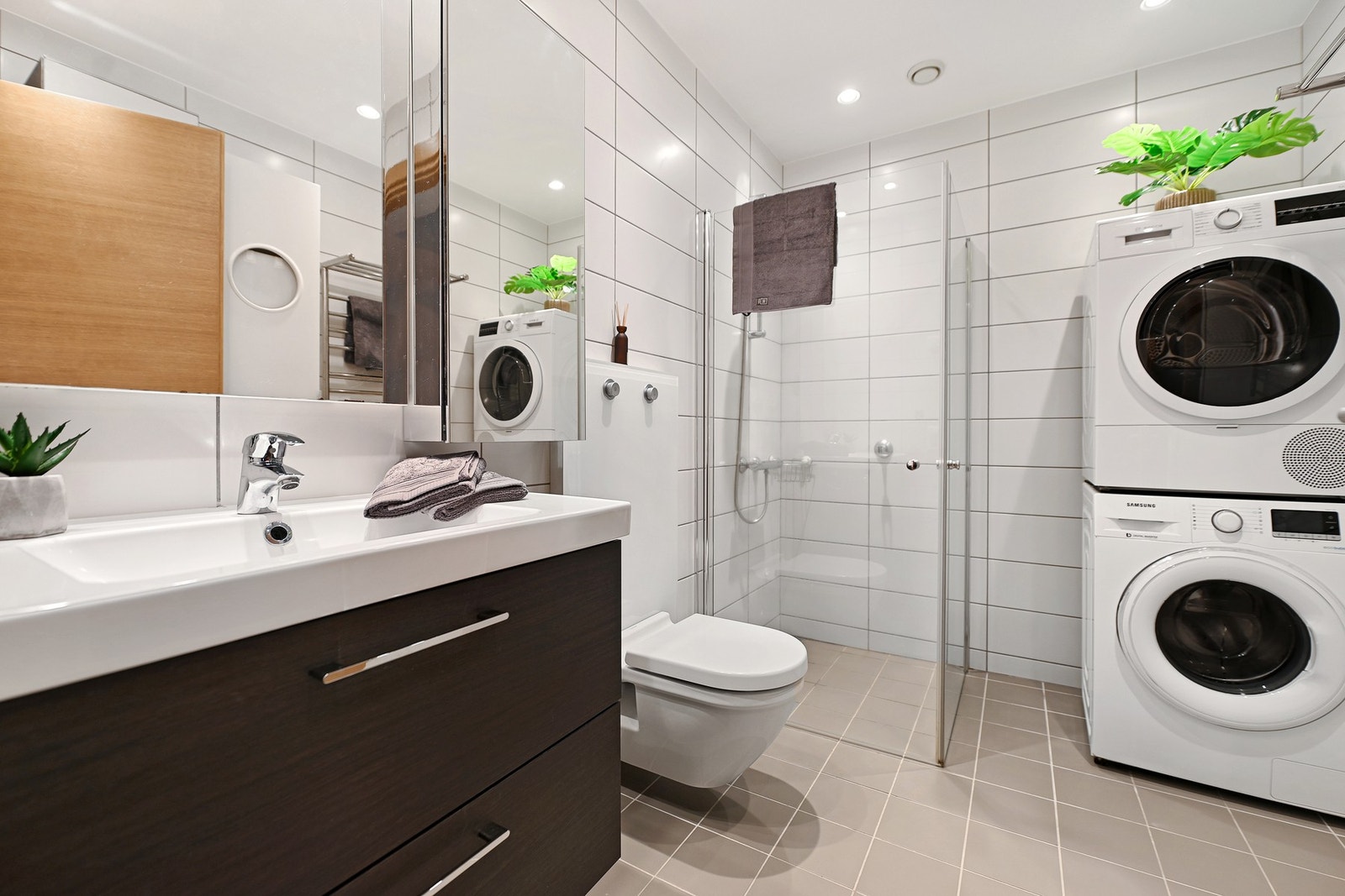 Badet i 1. etasje er innredet med nedfelt servant, veggfestet toalett, dusjhjørne og opplegg for vaskemaskin. Galleribilde