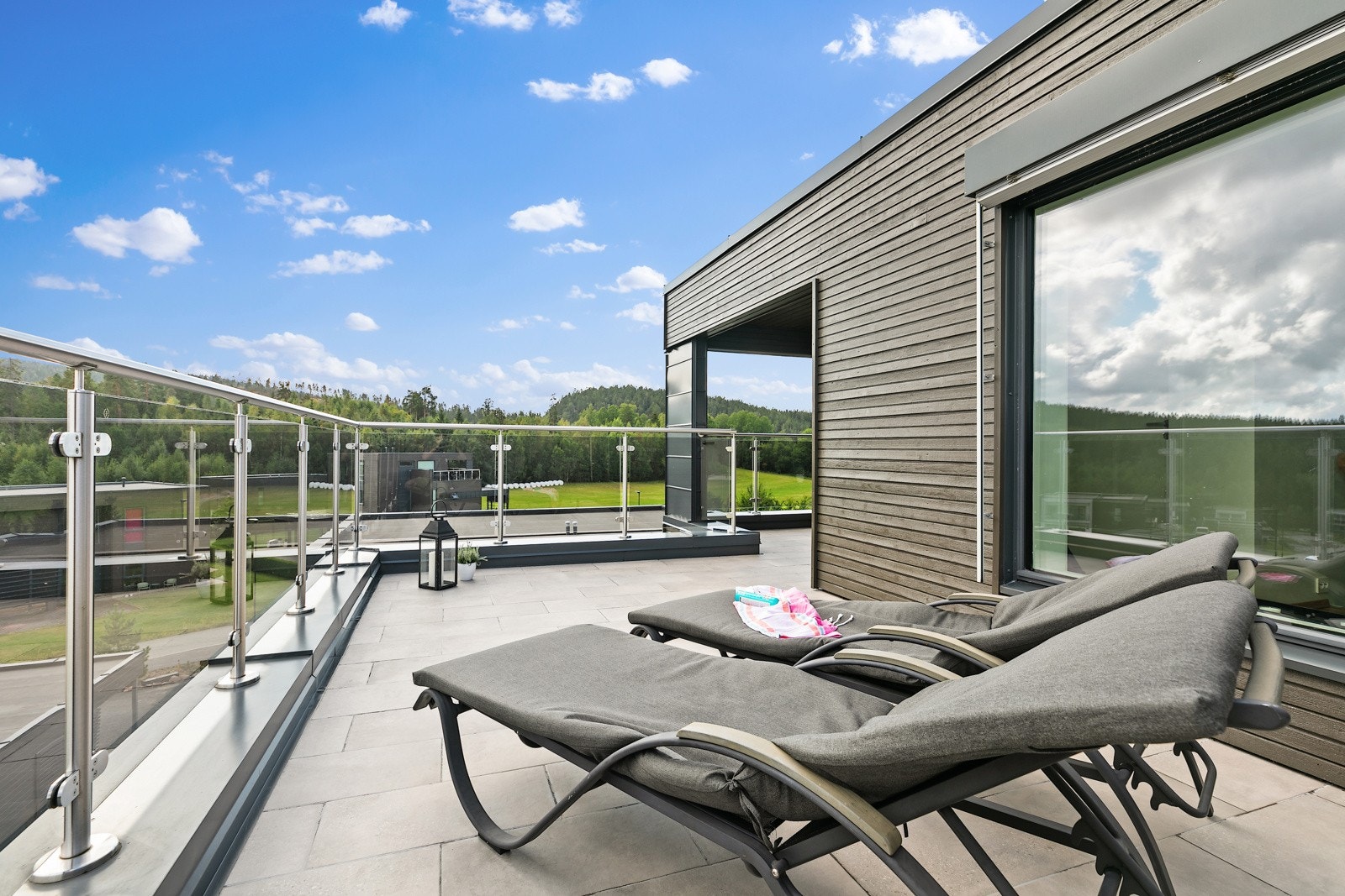 Takterrasse ideell for solstoler, med glassrekkverk og utsikt mot marka. Galleribilde