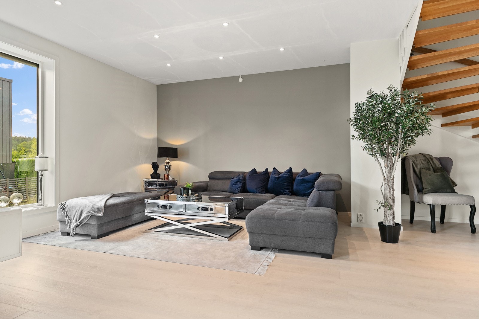 Dempet gråskala og lakkert parkett gir stuen et rolig og moderne uttrykk. Galleribilde