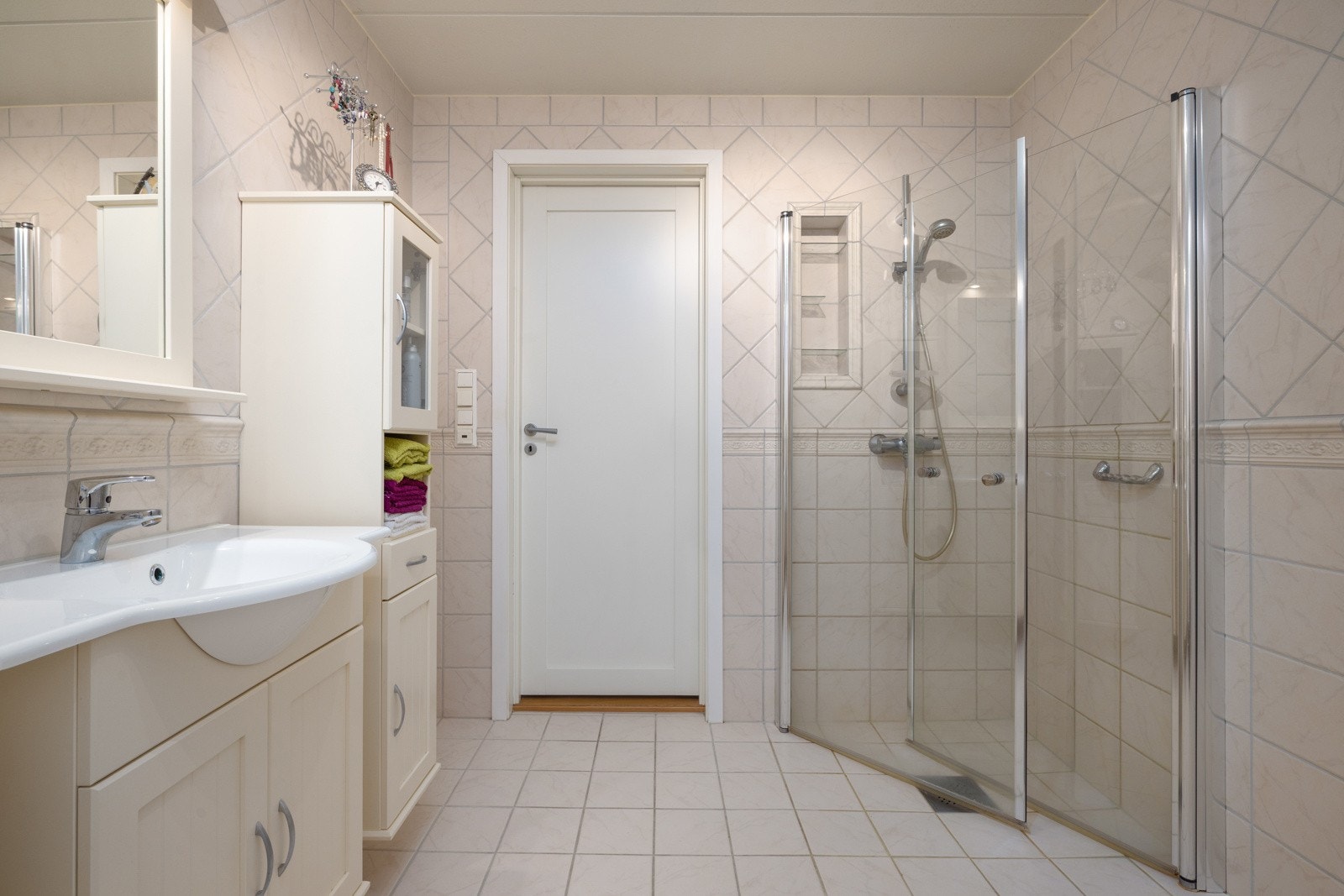 Badet er utstyrt med dusjhjørne med innfellbare glassdører, badekar, samt lyse baderomsmøbler med heldekkende servantplate. Galleribilde
