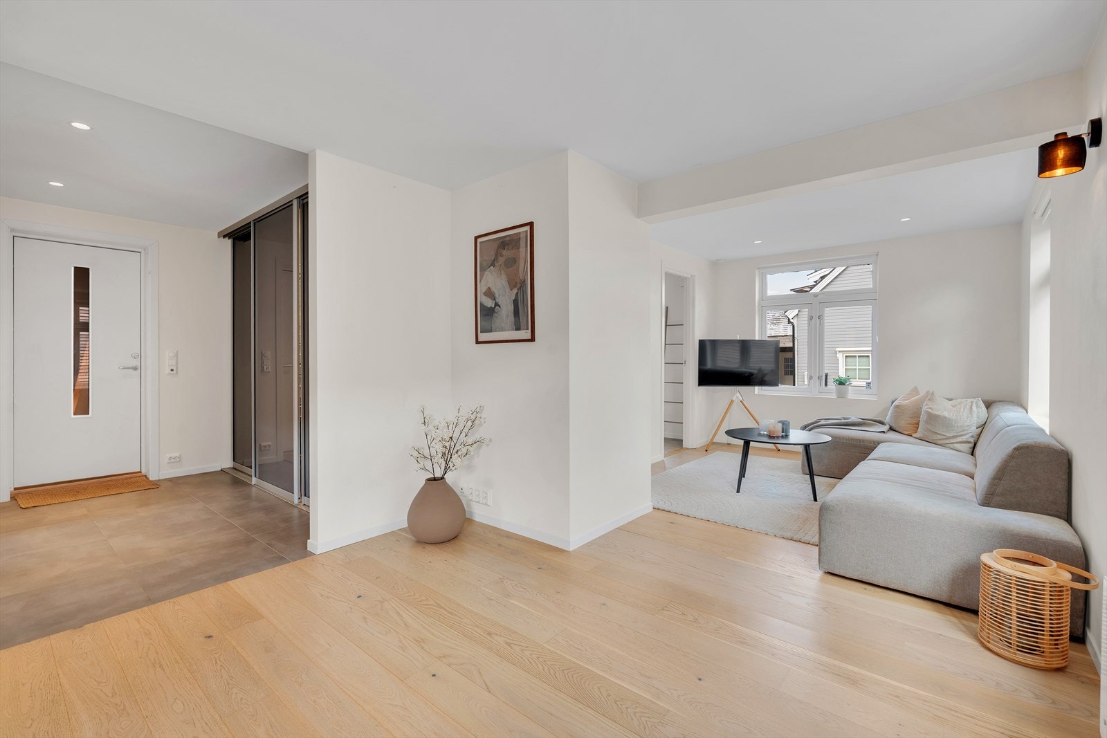 Lys og moderne stue med åpen løsning og store vinduer som slipper inn mye naturlig lys. Galleribilde