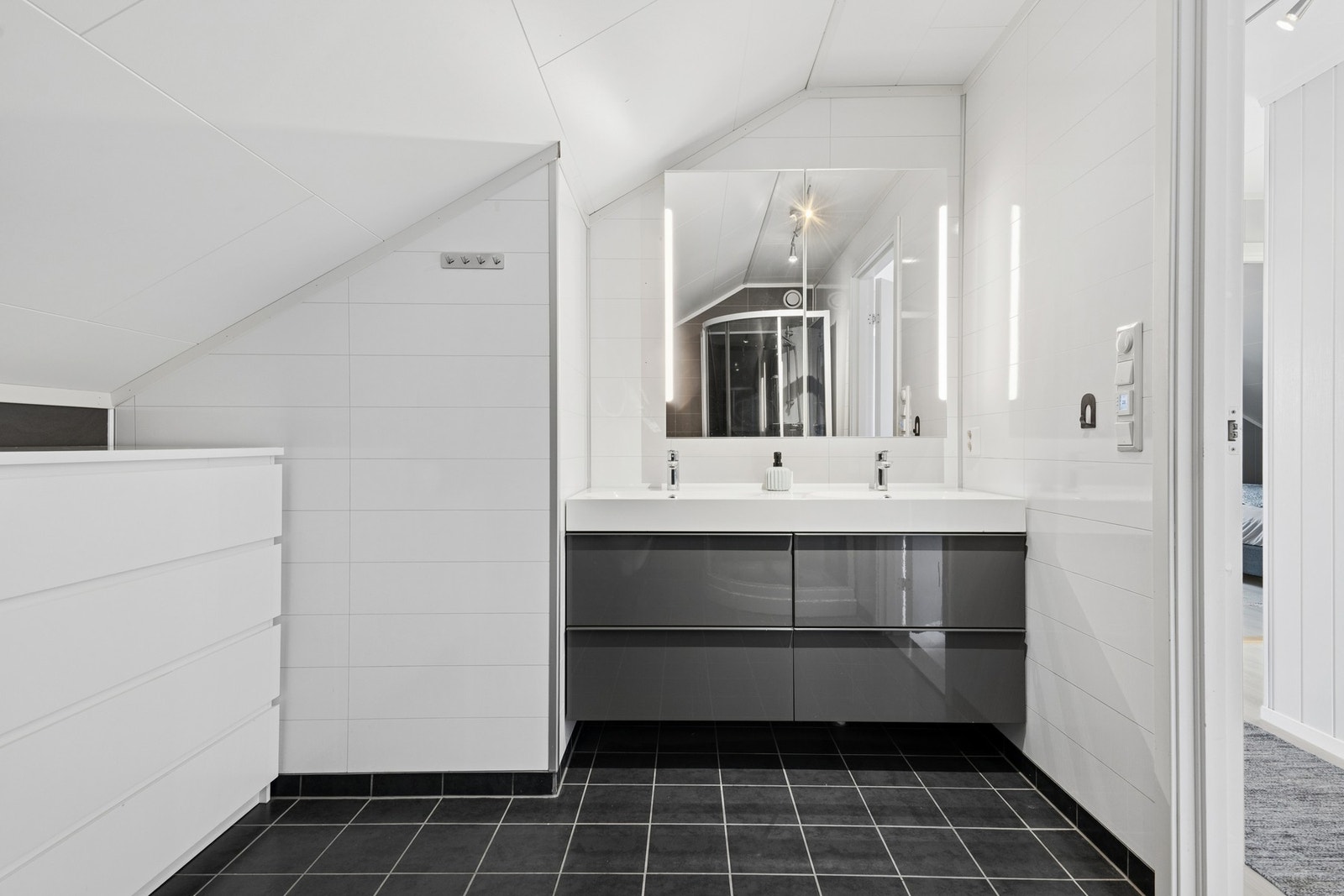 Badet i loftsetasjen er innredet med en bred servantseksjon med to servanter og speilskap med belysning. Galleribilde