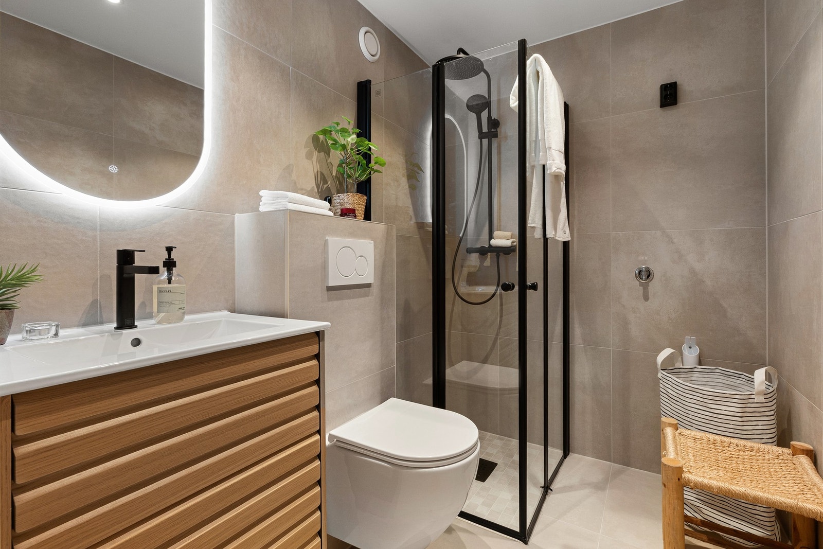 Badet er nytt i 2026 og fremstår strøkent, med moderne fliser, lune fargetoner og sorte detaljer Galleribilde