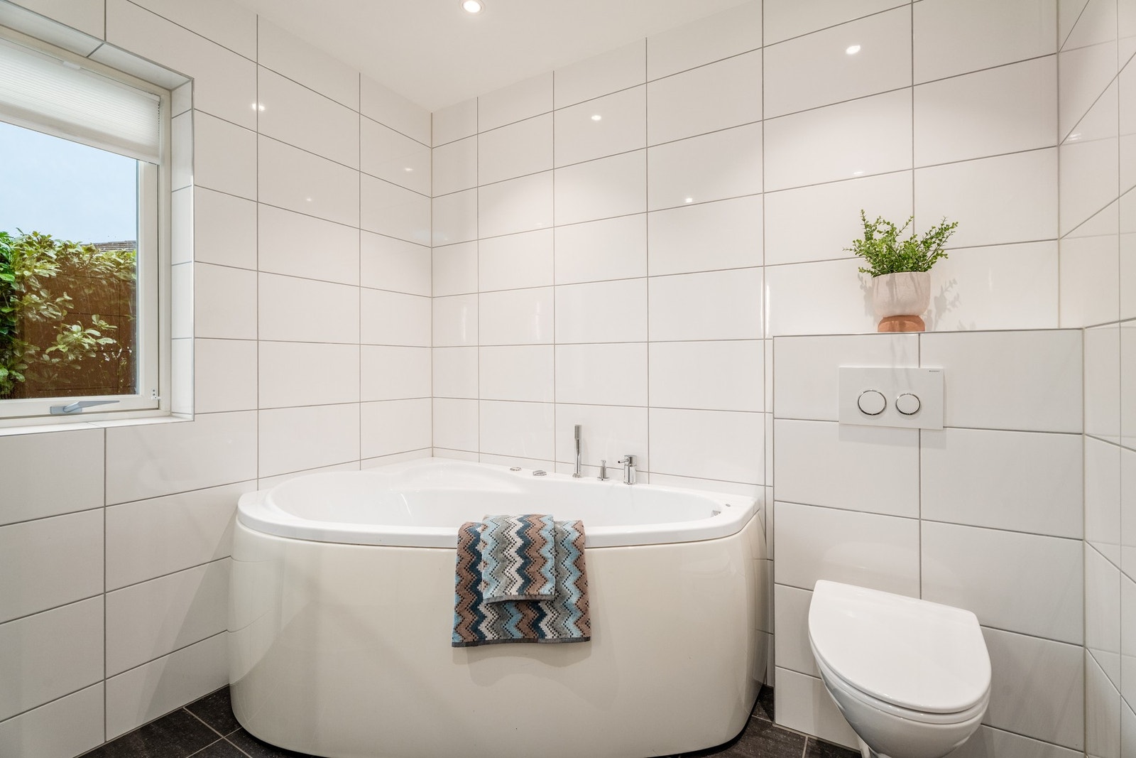 Badet i underetasjen har flislagte overflater, samt flislagt vinduspost, vegghengt WC og varmekabler i gulv. Galleribilde
