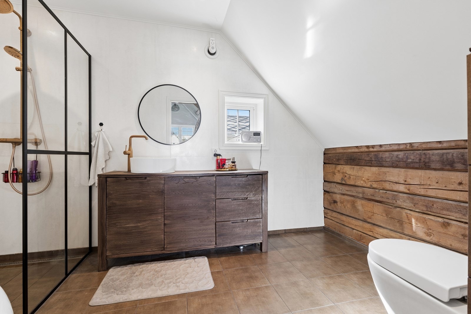 Badet har servant med innredning og veggmontert toalett. Rommet får et ekstra særpreg med den fine tømmerveggen. Galleribilde