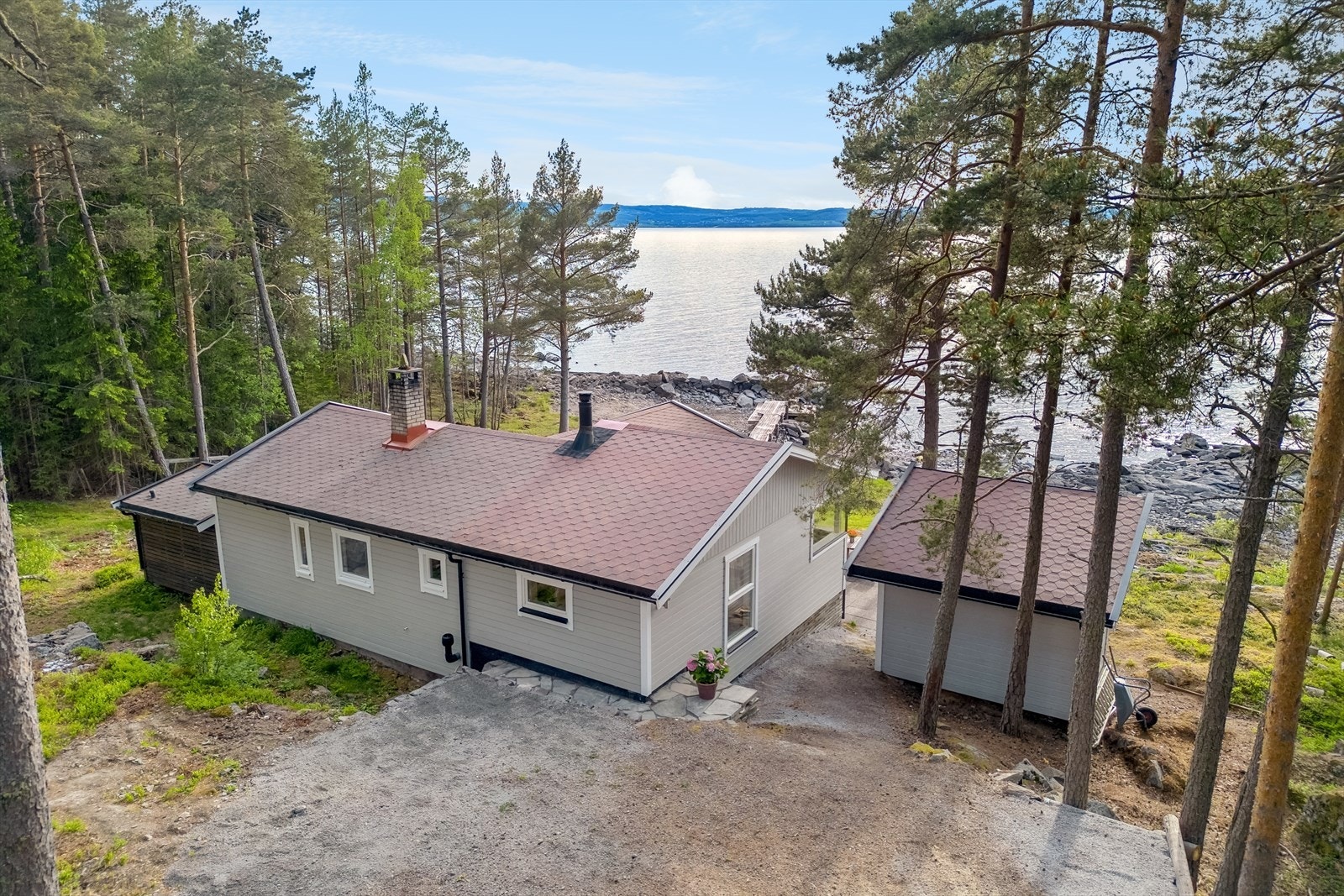 Sjarmerende fritidsbolig med idyllisk beliggenhet ved vannkanten. Plass til 3 bilder på gruset biloppstillingsplass. Galleribilde