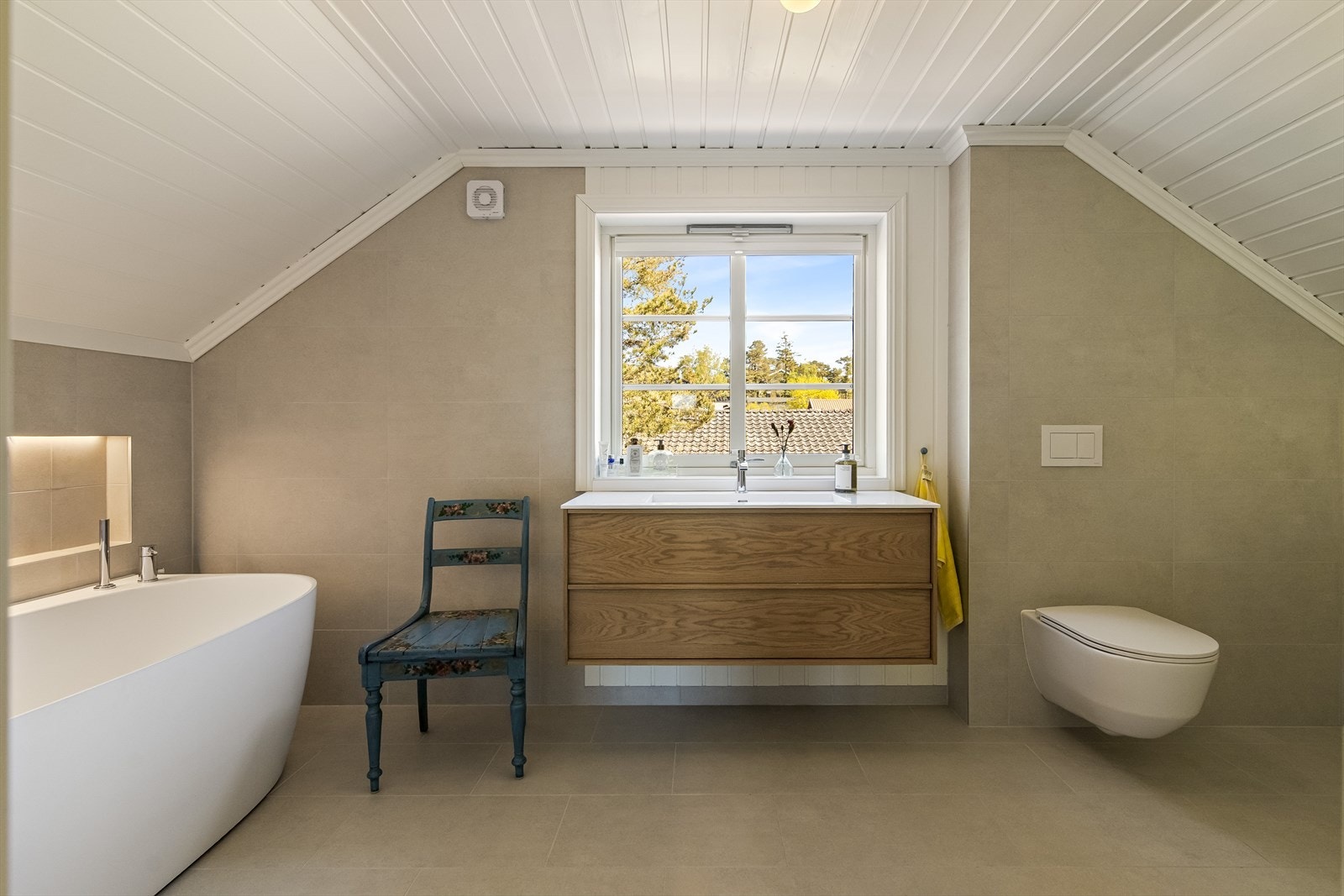 Badet i 2. etasje har en herlig, avslappende atmosfære, der store, lyse gulvfliser kombineres med matchende fliser og hvitmalte paneler på veggene. Galleribilde