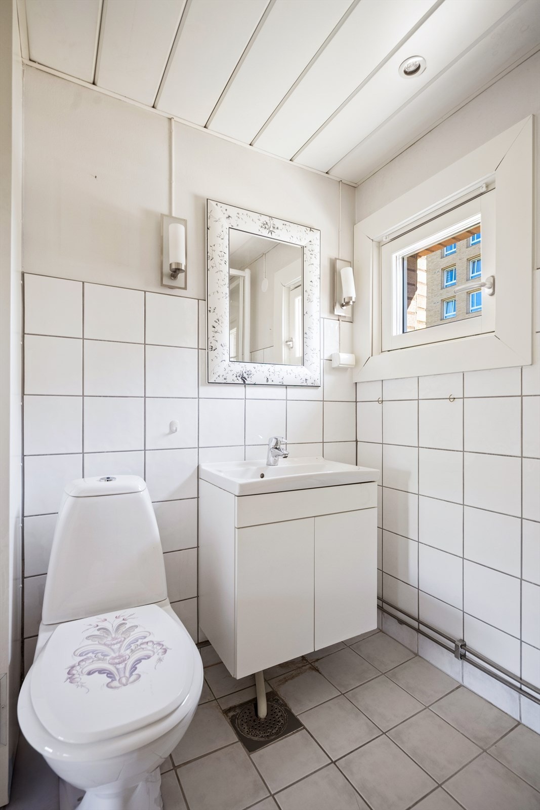 Badet er innredet med gulvstående toalett, dusjkabinett og baderomsinnredning med nedfelt servant, skap og speil. Galleribilde