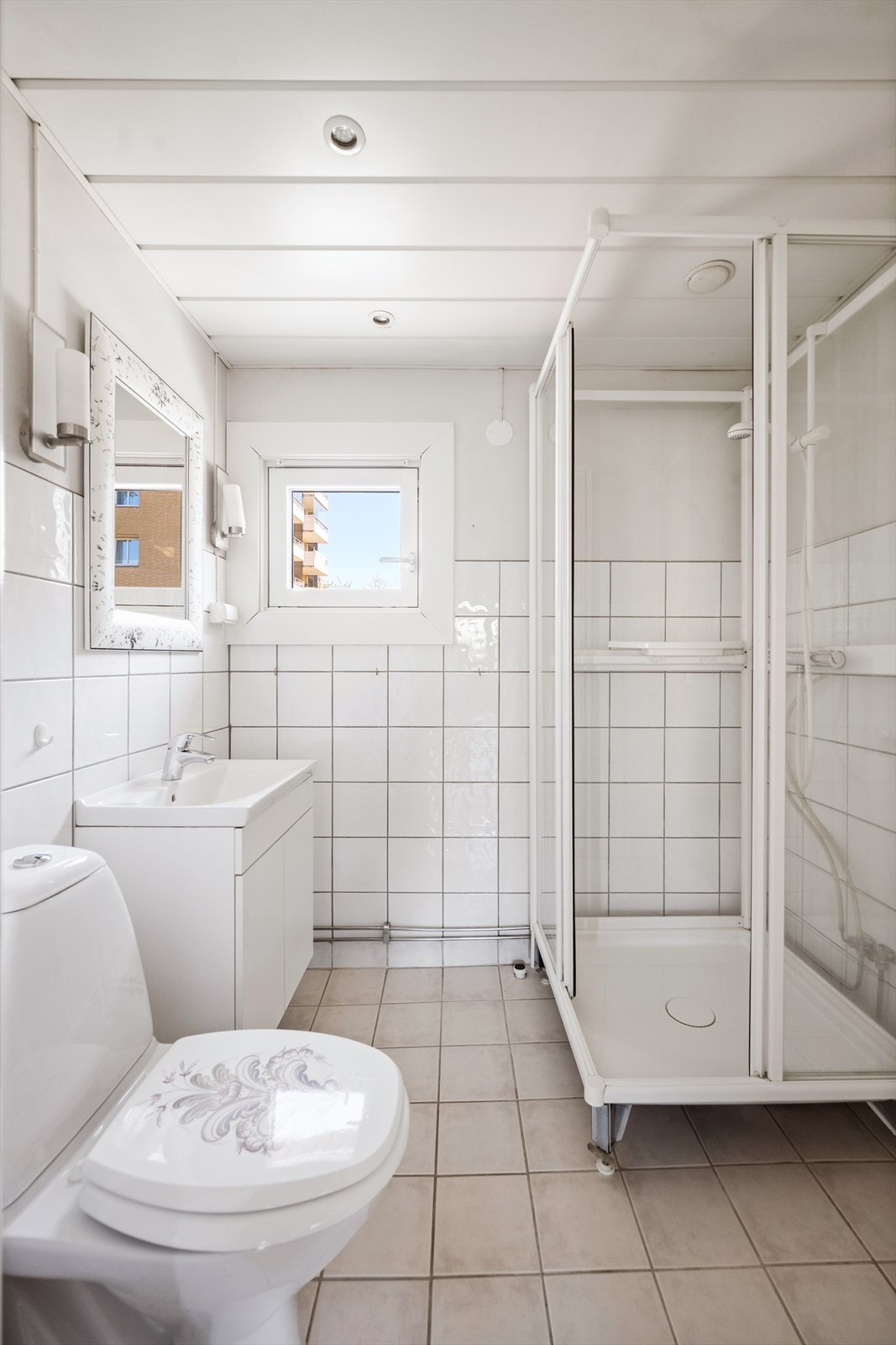 Badet har flislagt gulv, en kombinasjon av flislagte og malte vegger og himling med downlights. Det er opplegg for vaskemaskin. Galleribilde