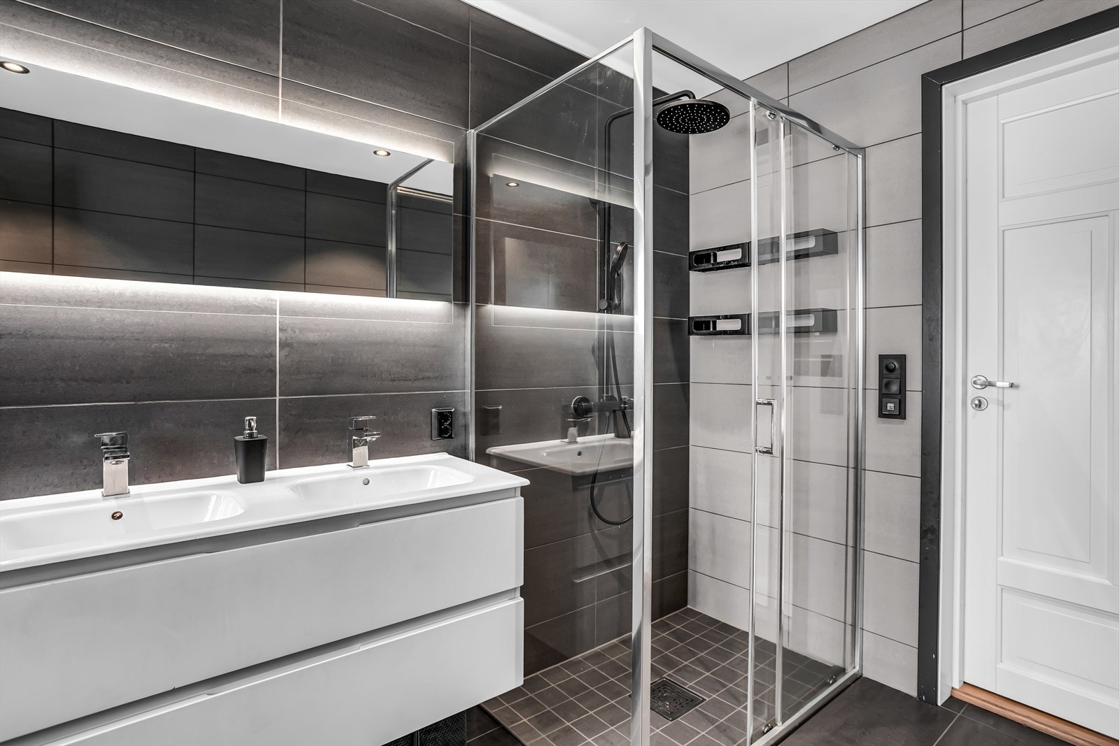 Badet er utstyrt med dobbelservant, vegghengt toalett og dusjhjørne med glassvegger. Galleribilde