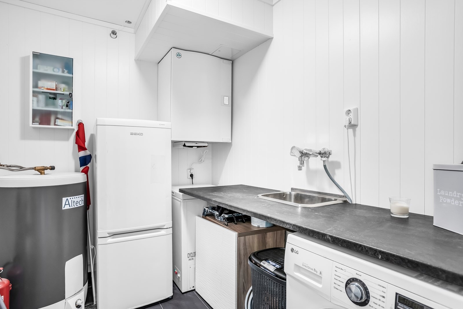 Praktisk vaskerom med flislagt gulv med varme, utslagsvask og opplegg for vaskemaskin. Galleribilde