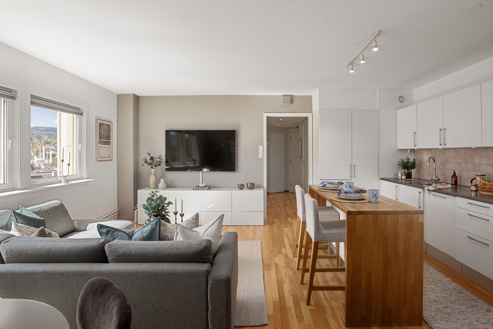 Parkett på gulvet kombineres med vegger malt i hvitt og en dus gråtone. Galleribilde