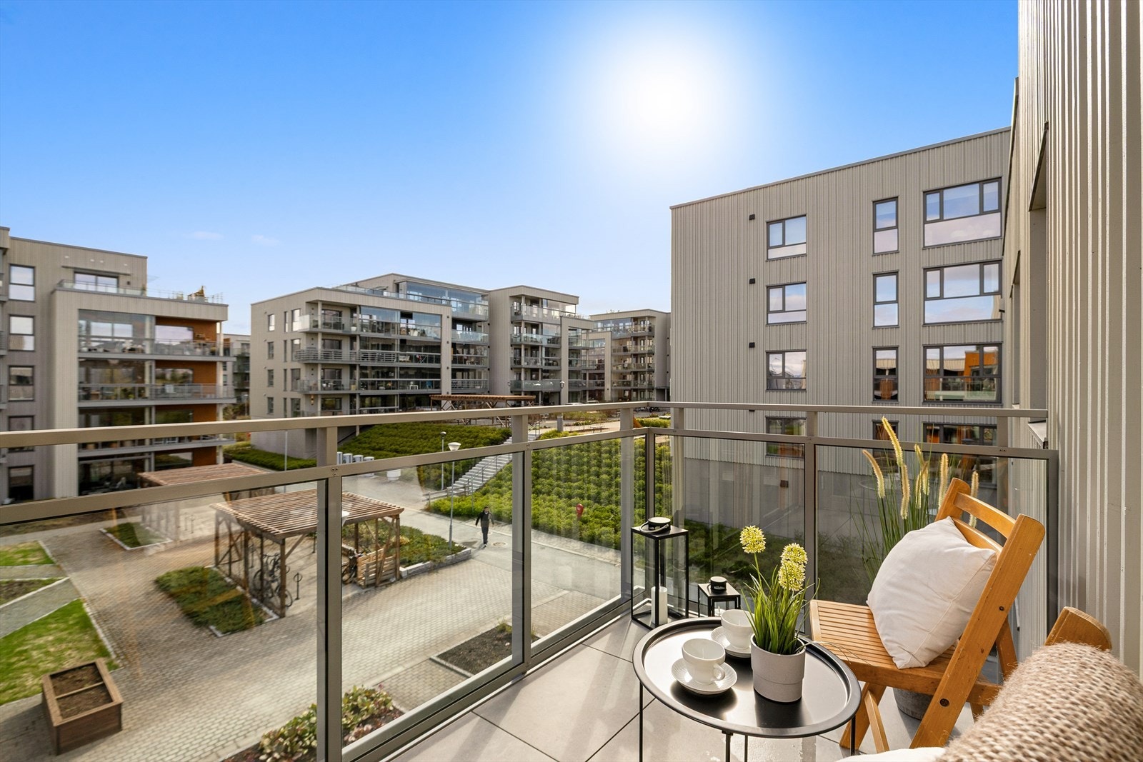 Leilighetens balkong vender mot rolige fellesareal i sameiet. Her er det god avstand mellom boligblokkene, og grønn beplantning som vokser seg fin på sommerstid. Galleribilde
