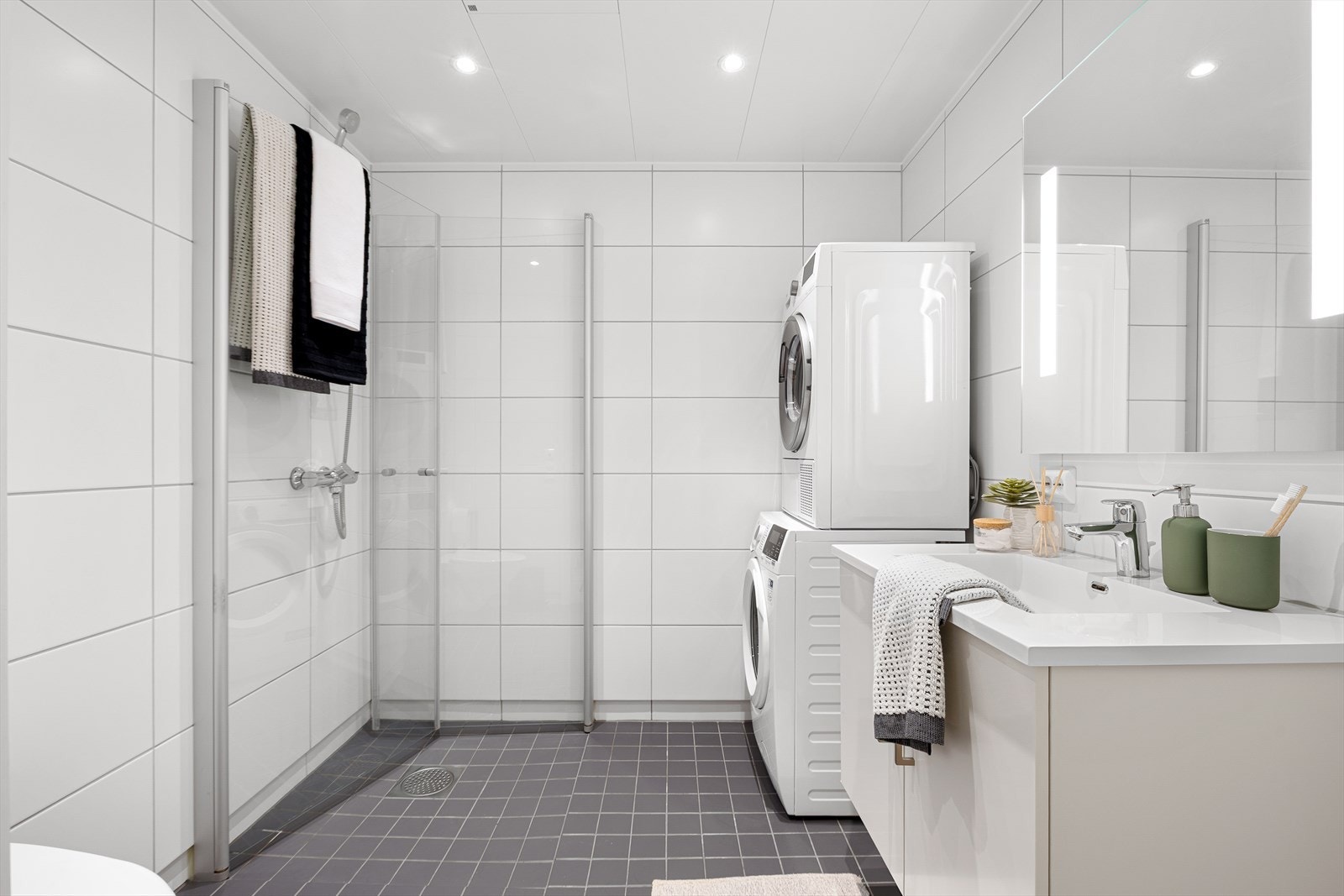 Det 4 m² innbydende badet har helflisede overflater, behagelig gulvvarme og downlights i tak. Det er utstyrt med innfellbare dusjdører, mekanisk avtrekk, veggmontert toalett, servant i skap, samt rørfordelerskap, vannmåler og energimåler. Galleribilde