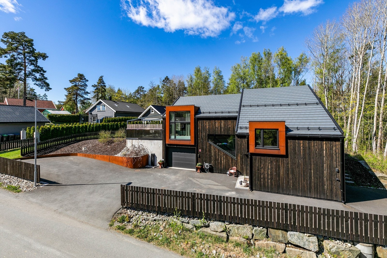 Stakittgjerde rundt gårdsplassen og del av hagen er beiset i samme nyanse som boligens kledning. Galleribilde