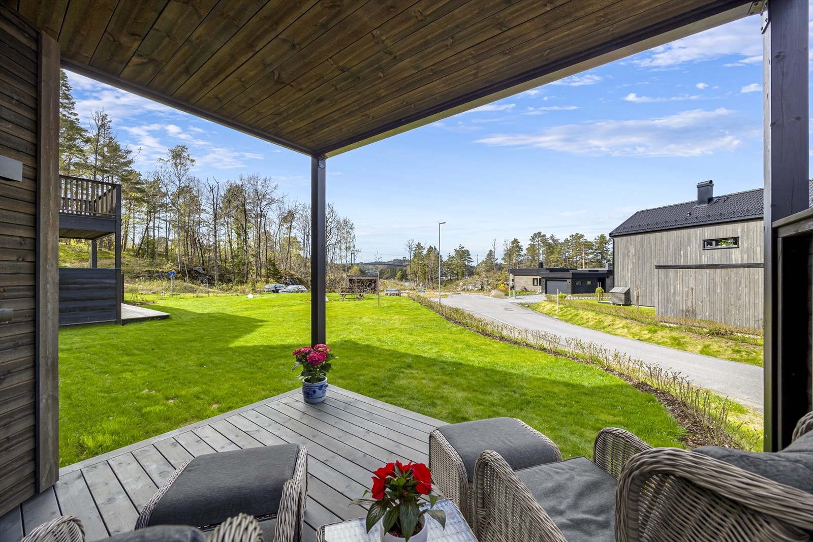 Fra terrassen er det utsyn over grøntarealer og nabolaget, som gir en åpen atmosfære. I tillegg noe utsikt mot sjøen. Plen og hage disponeres av boligen som selges. Galleribilde