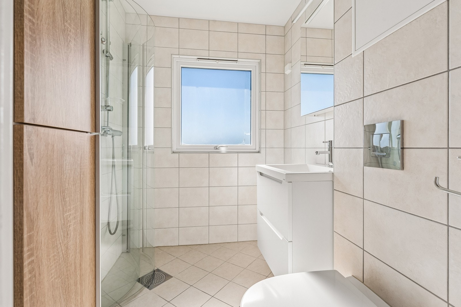 Badet består av vegghengt toalett, servant med skuffer og dusj i hjørne med innadslående dører. Galleribilde