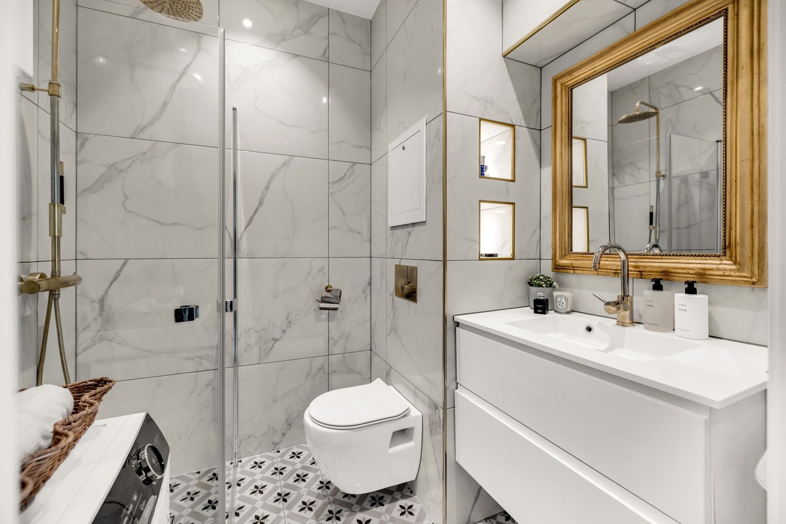 Badet er innredet med vegghengt toalett og servantinnredning med ovenpåliggende vask og speil over vasken. Galleribilde