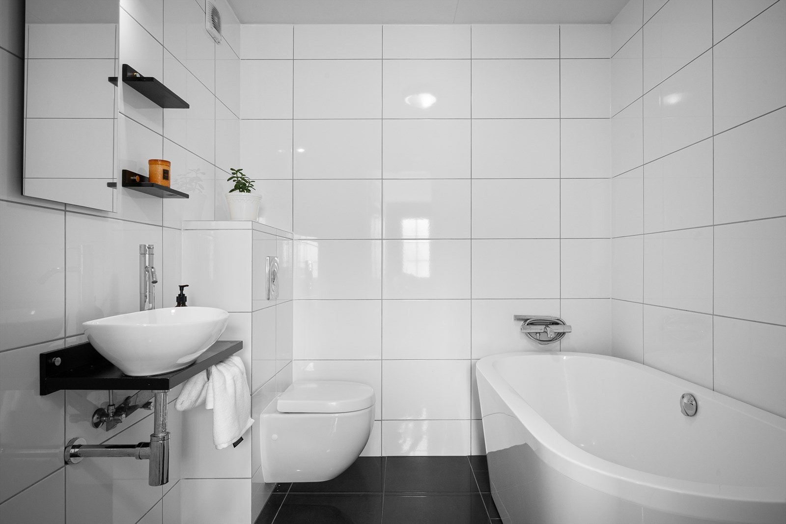 Badet i første etasje er helfliset og utstyrt med badekar, vegghengt toalett og servant. Galleribilde