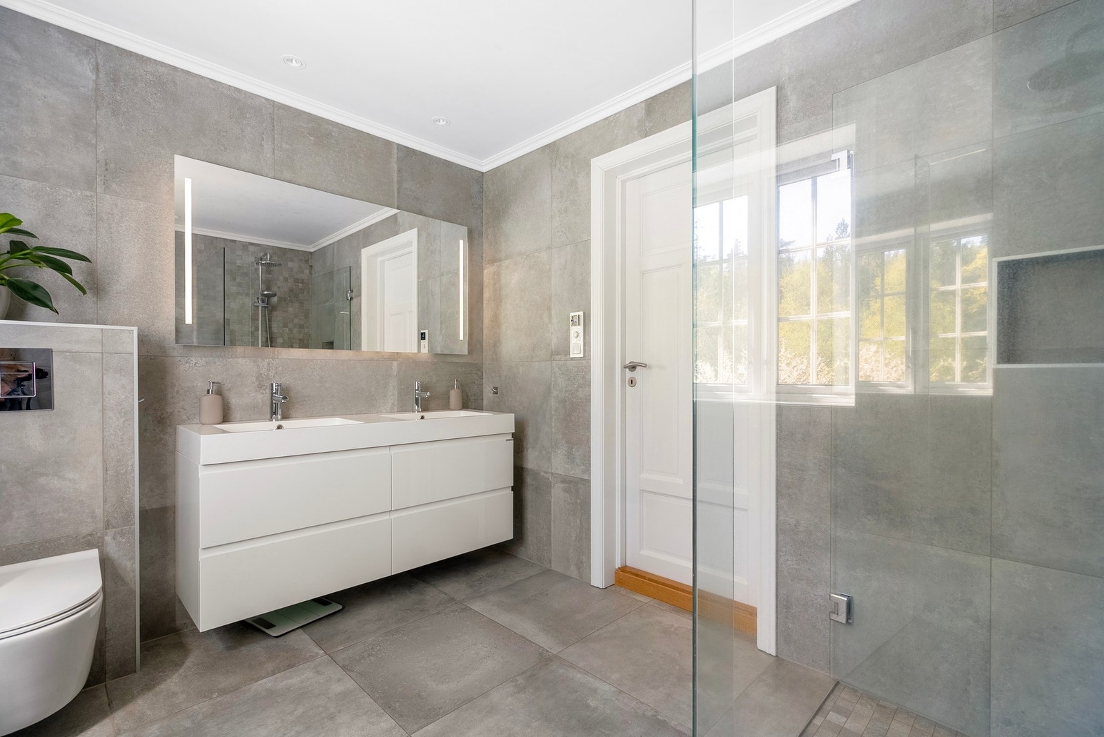 Badet har vegghengt innredning, dusjløsning med glassvegger og behagelig naturlig lys fra vindu. Et tidløst og funksjonelt rom med eksklusivt preg. Galleribilde