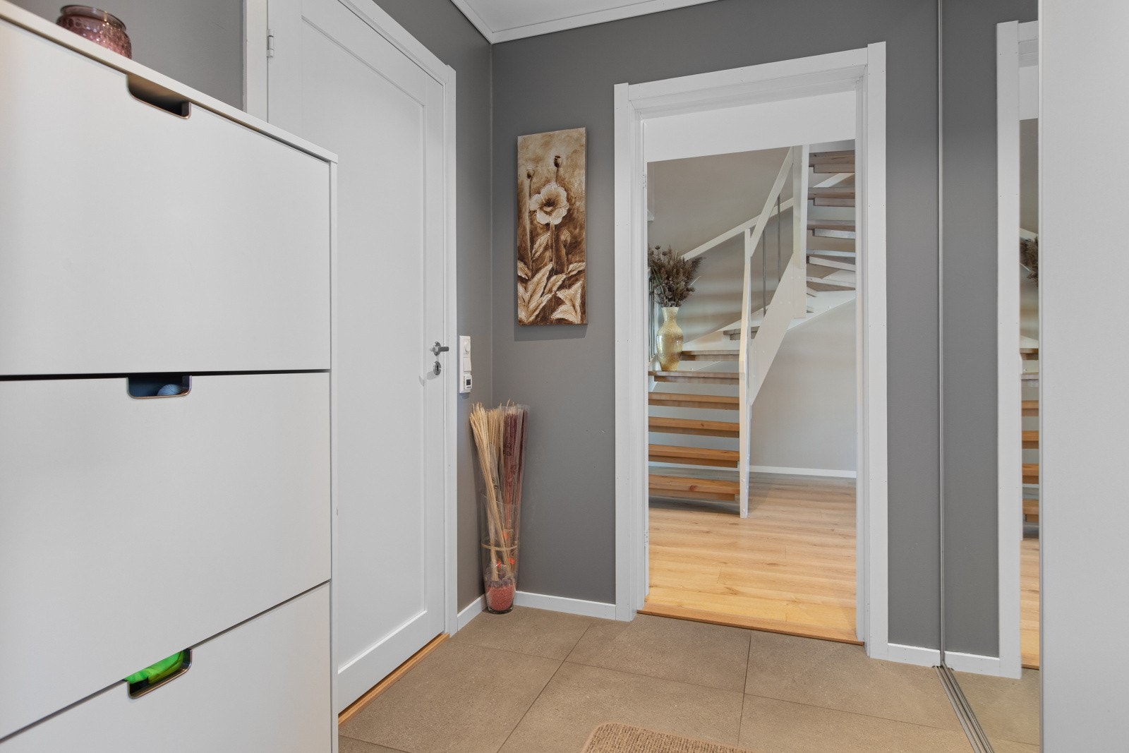 Skyvedørsgarderobe med speil langs veggen gir rommet dybde, og det er god plass til skohyller på andre siden av rommet. Galleribilde