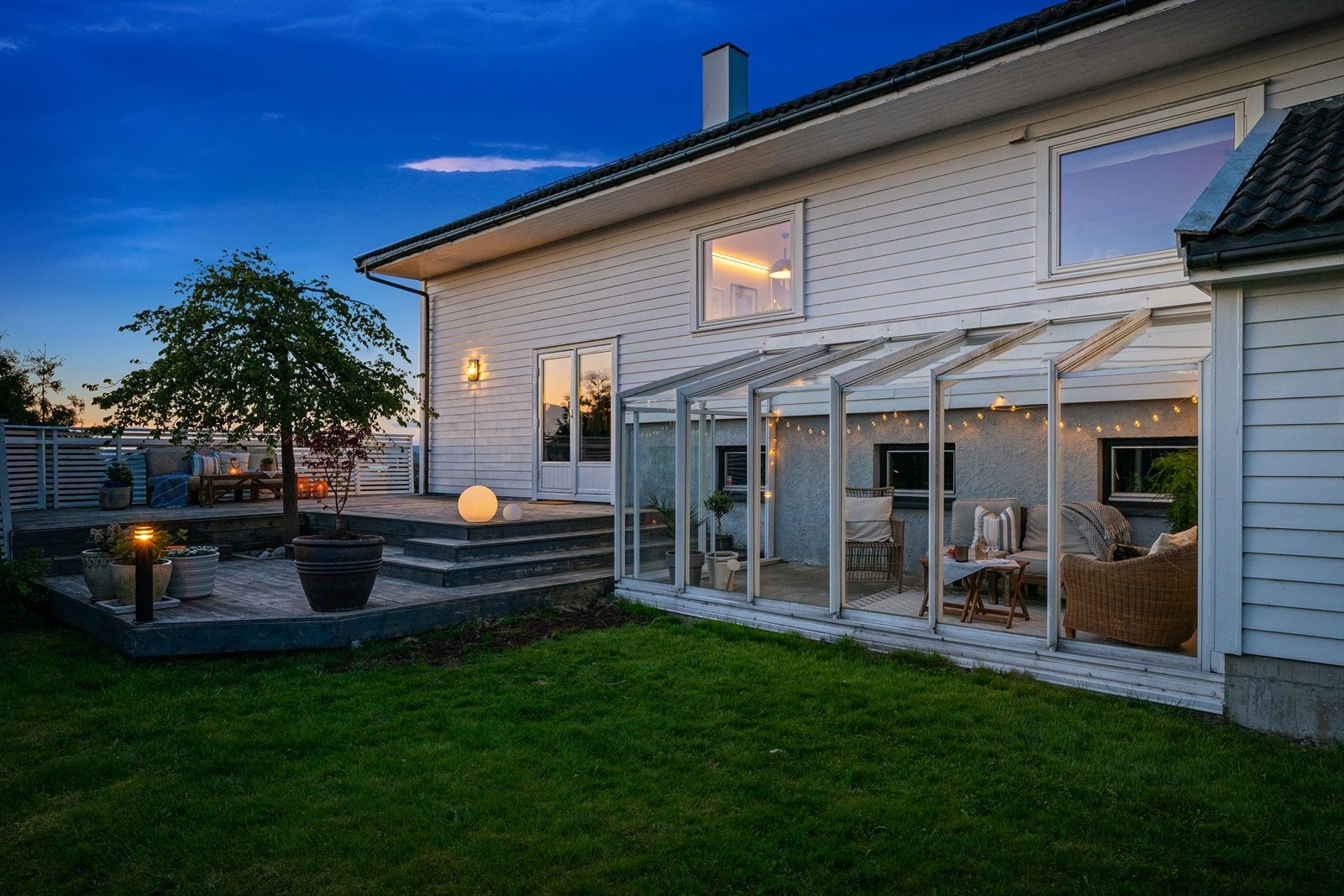 Boligen med hage og terrasse sett fra hagen på kveldstid. Galleribilde