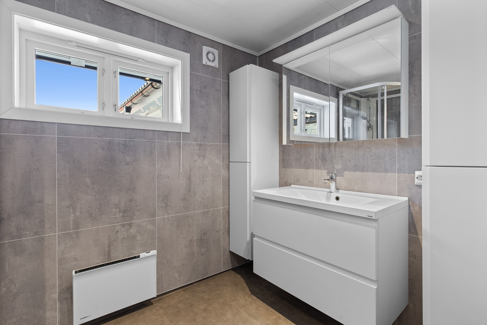 Badet er innredet med servant med skuffer, skap og speil. Galleribilde
