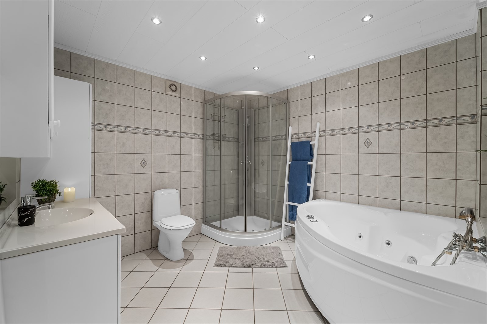 Baderom i underetasjen, med fliselagte gulv og vegger. Badet er utstyrt med baderomsinnredning, toalett, boblebad og dusjkabinett. Galleribilde