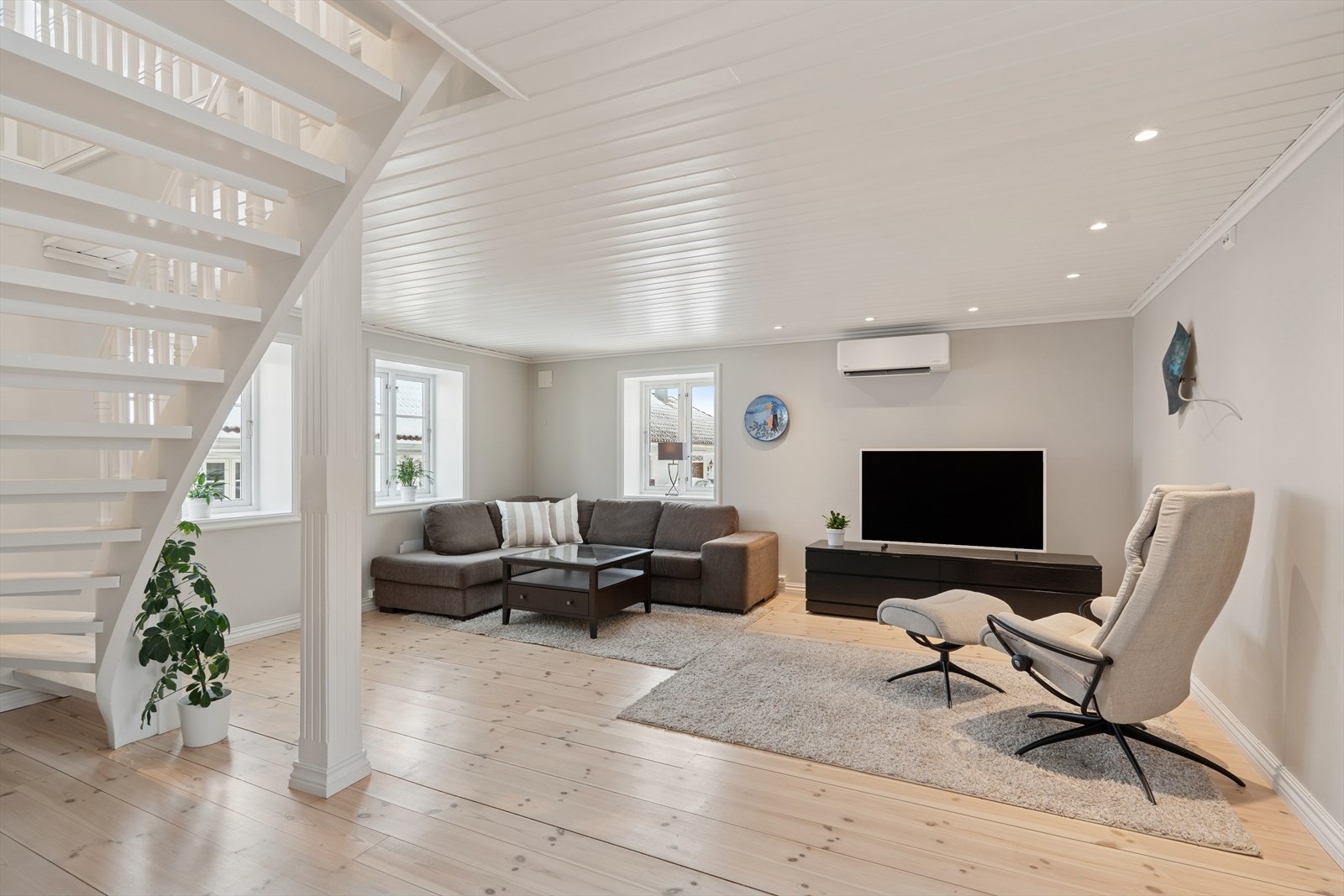 I stuen er det heltre furugulv. Tapet på veggene og malt panel med downlights i himling Galleribilde