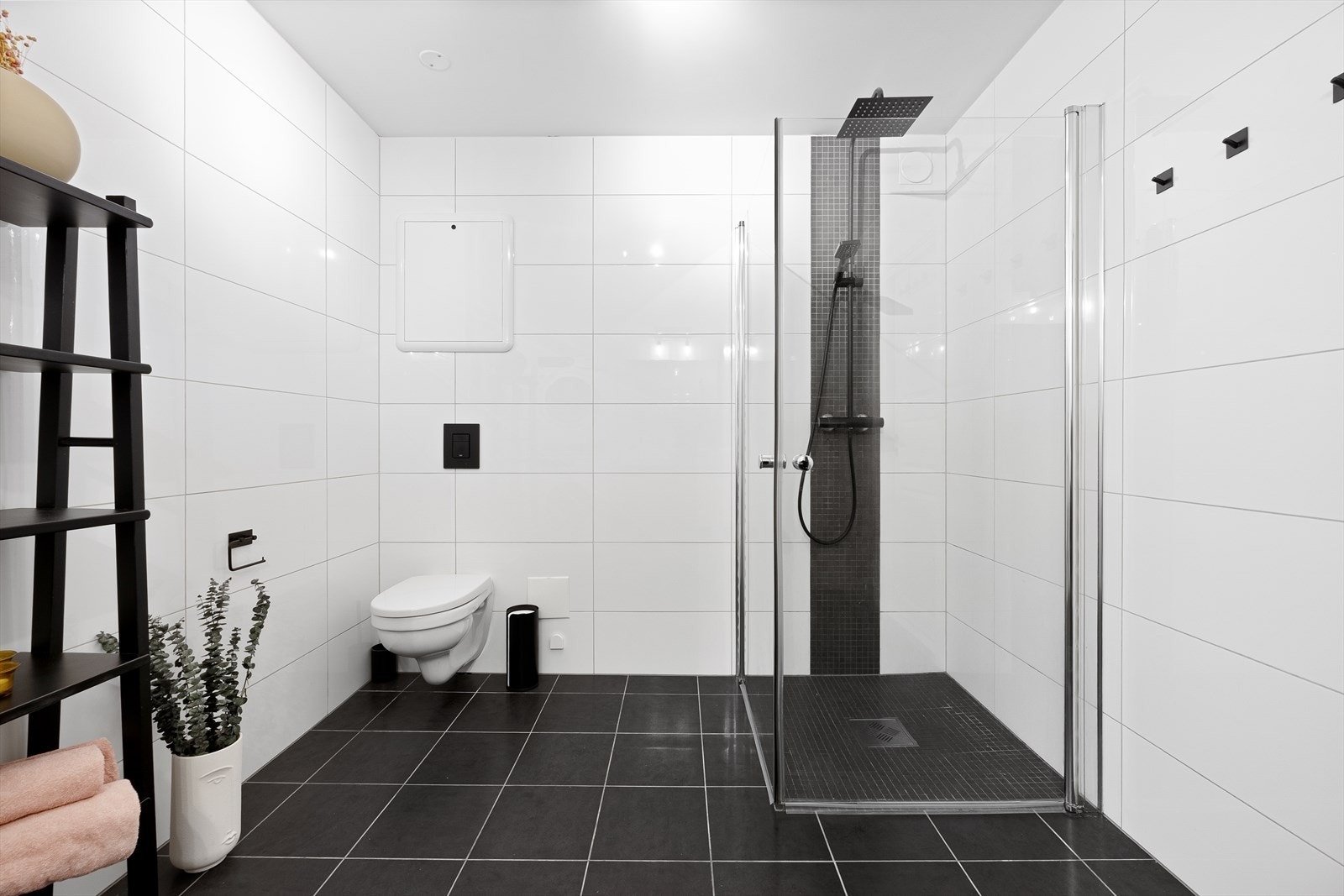 Badet har veggmontert toalett og et romslig dusjhjørne med glassvegger. Galleribilde