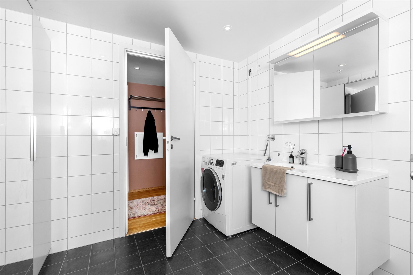 Badet har opplegg for vaskemaskin og er utstyrt med servantinnredning og speilskap. Galleribilde