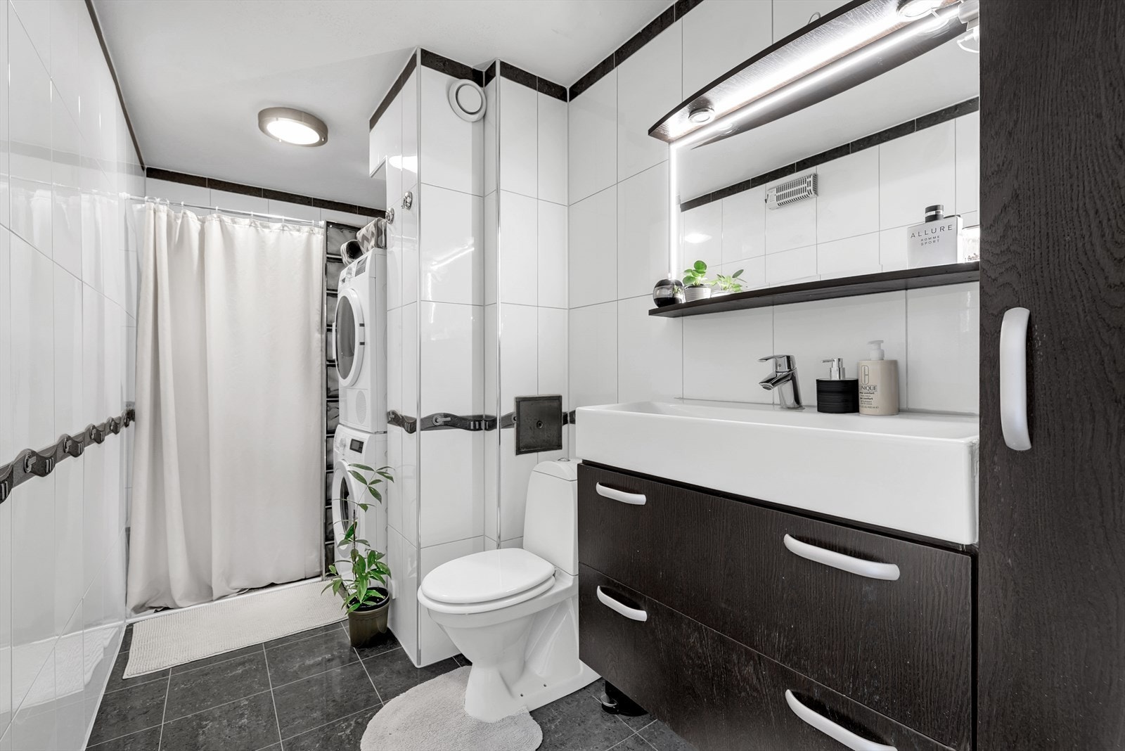 Badet har flislagte overflater, dusjhjørne og praktisk opplegg for vaskemaskin. Varmtvann er inkludert via fellesanlegg. Galleribilde