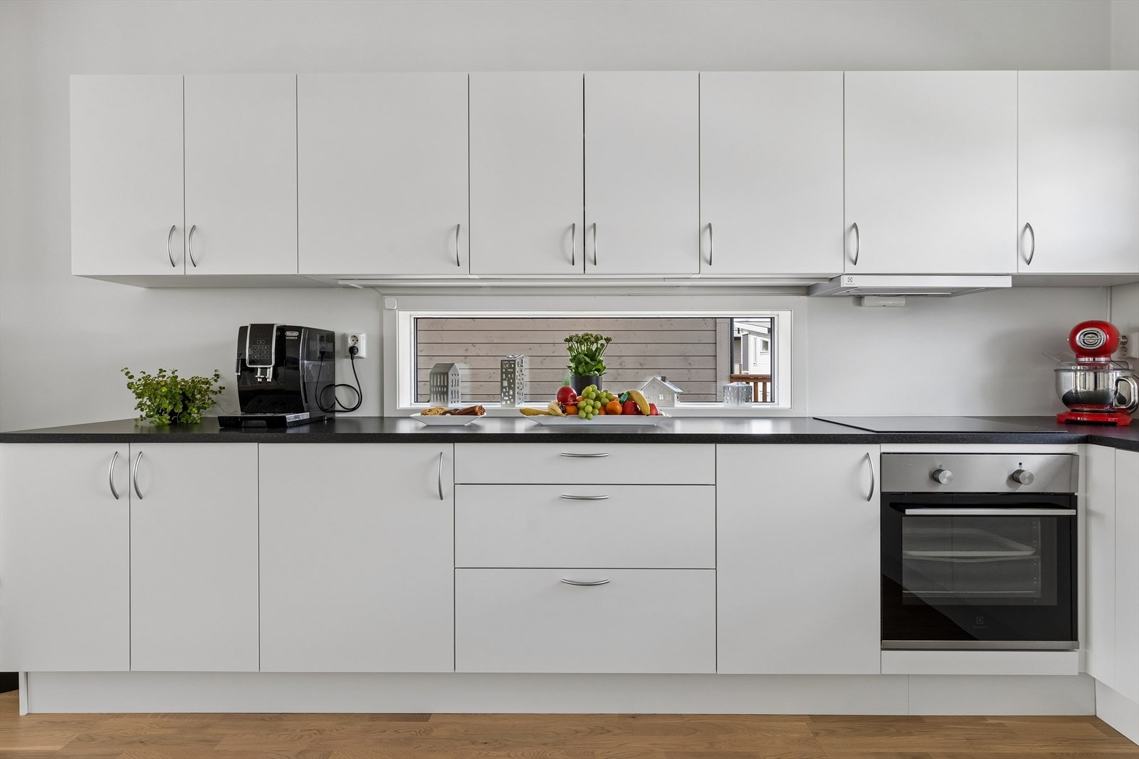 Innredningen har hvite, glatte fronter og laminert benkeplate i sort design med nedfelt oppvaskkum. Galleribilde