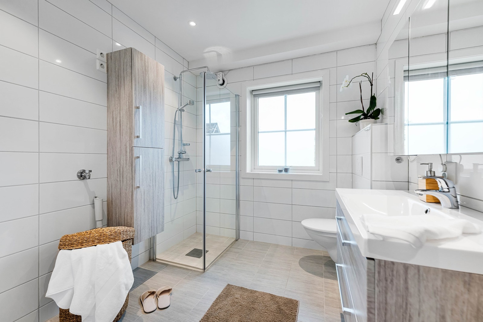 Badet er romslig, og er innredet med baderomsmøbler, vegghengt wc og dusjhjørne med dører. Gode oppbevaringsmuligheter både i speilskap, underskap og høyskap. Opplegg for vaskemaskin. Galleribilde