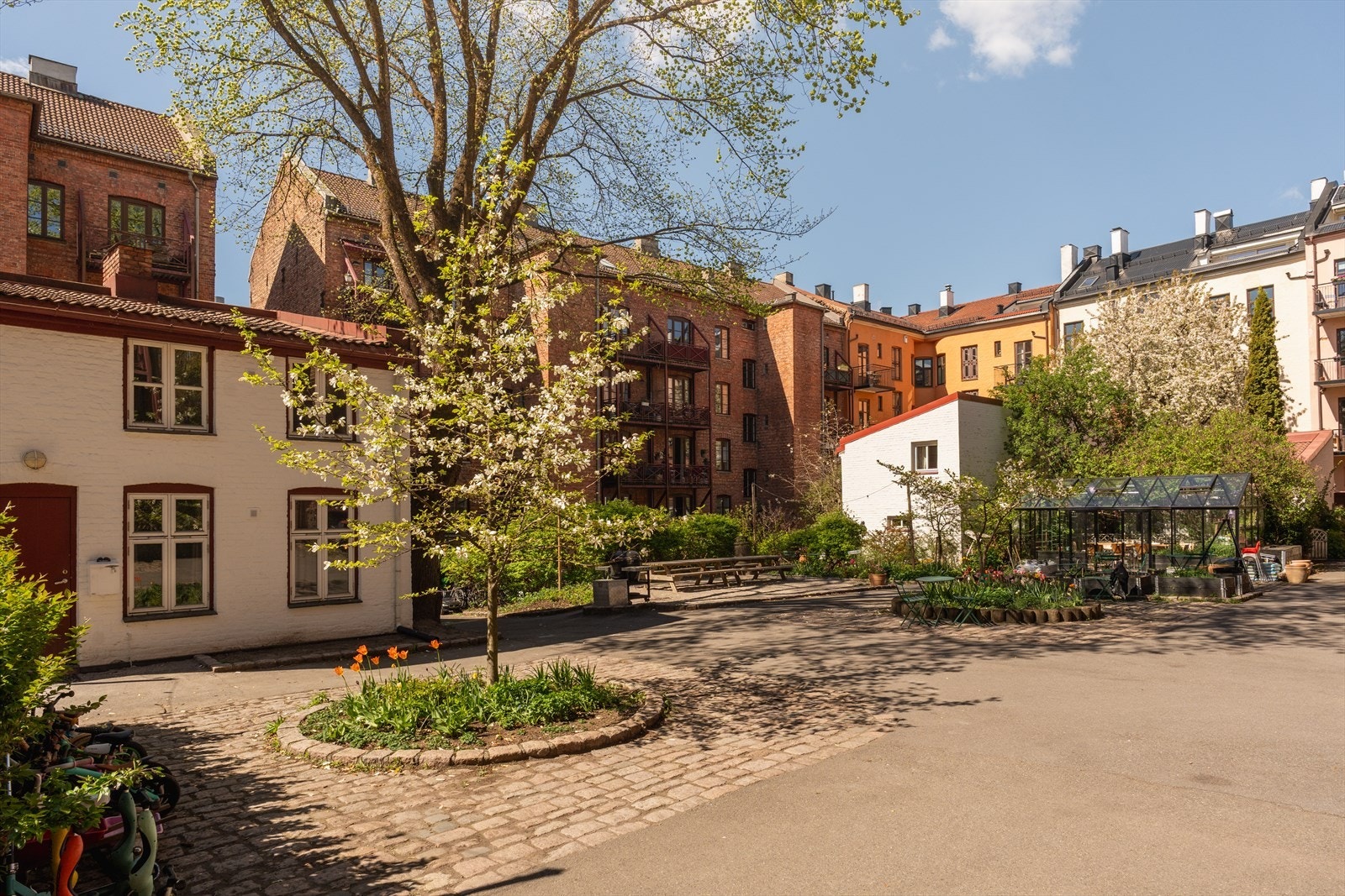 De historiske teglsteinsbygningene skaper en unik ramme rundt det frodige gårdsrommet. Galleribilde
