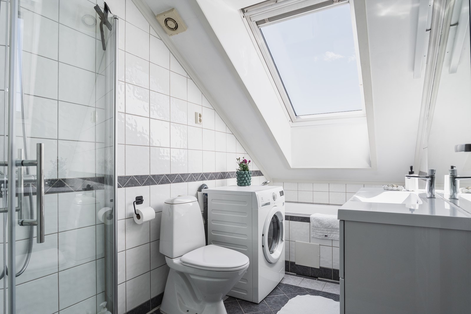 Flislagt bad med elektriske varmekabler i gulvet, badekar og opplegg for vaskemaskin. Galleribilde