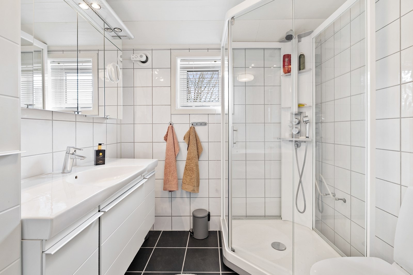 Flislagt bad med varmekabler i gulvet. Rommet har baderomsinnredning med nedfelt servant, speilskap med integrert belysning, toalett og dusjkabinett. Galleribilde