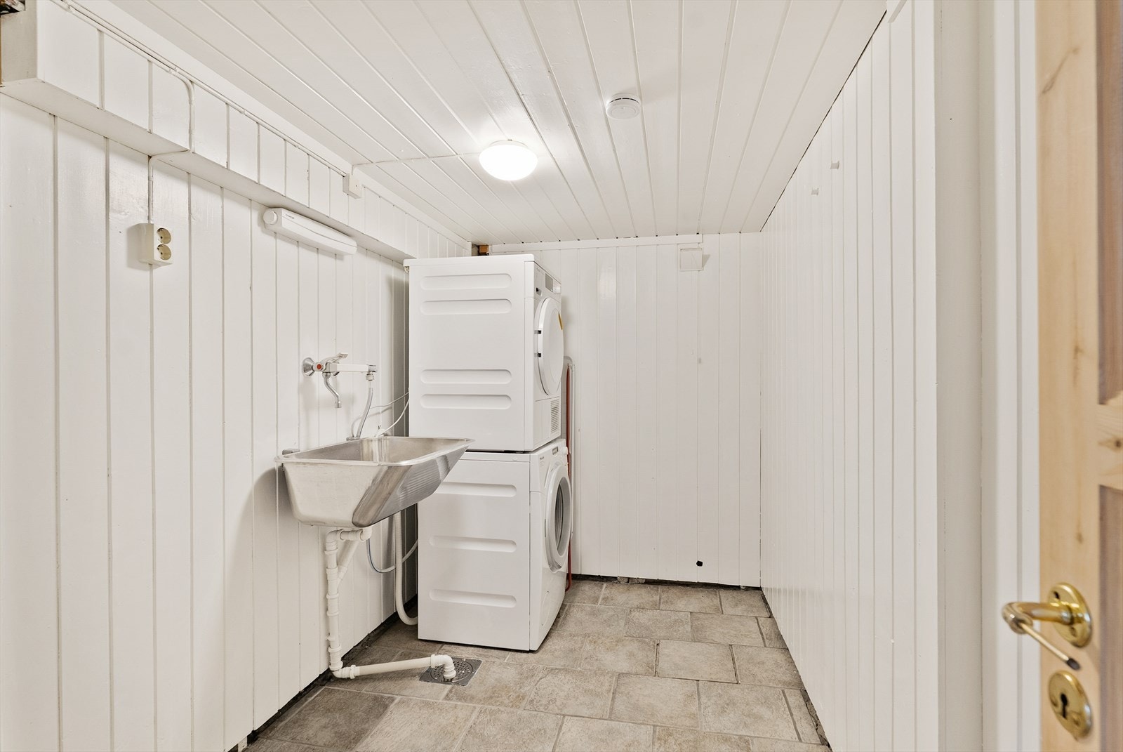 Vaskerommet har vegger med panel/tømmer og flislagt gulv med varmekabler. Rommet har stålvask og opplegg for vaskemaskin. Galleribilde
