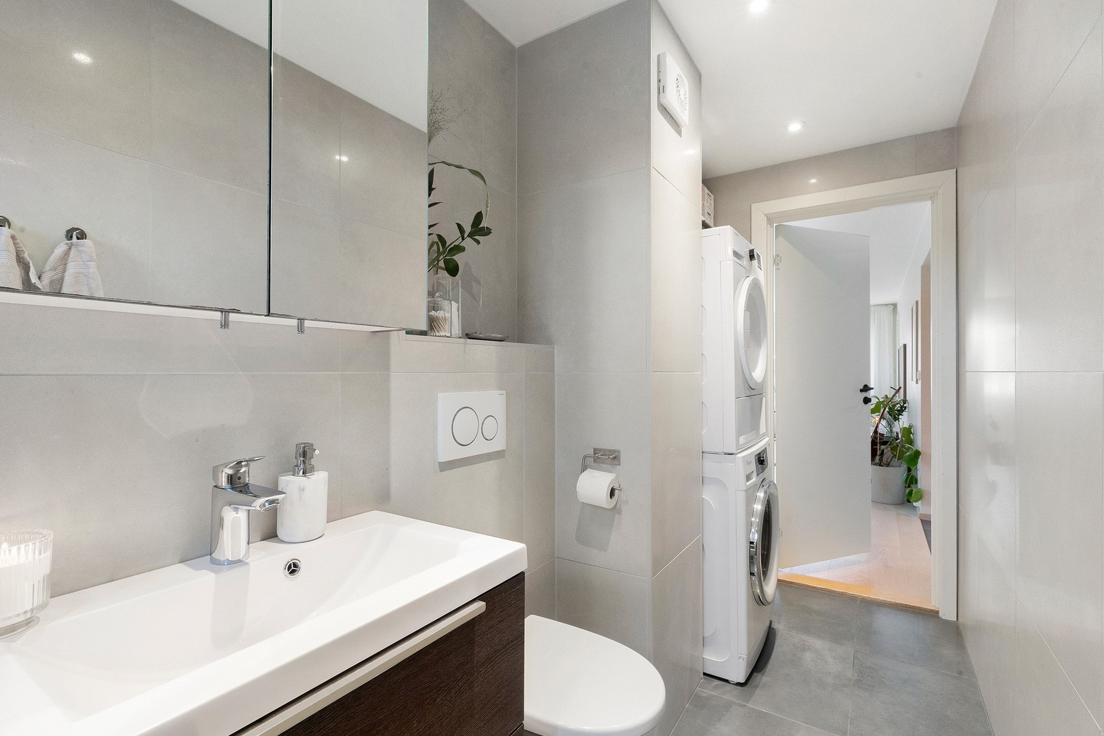Badet er utstyrt med vegghengt WC, opplegg for vaskemaskin og tørketrommel, servantskap, speilskap og dusjnisje med skyvedør. Galleribilde