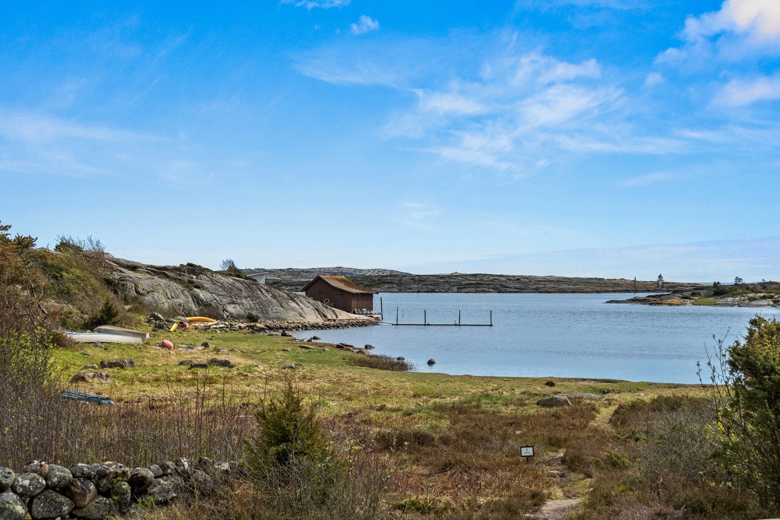 Tomten grenser ned mot sjøen og har badeplass samt naust beliggende i bakkant (Hvitt bygg bak det ytterste naustet) Galleribilde