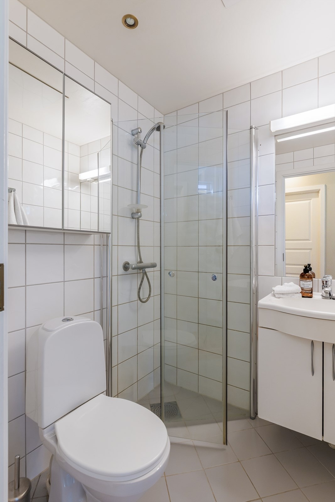 Videre er det gulvstående toalett, 60 cm servant med underskap og dusjhjørne med innfellbare glassvegger. Galleribilde