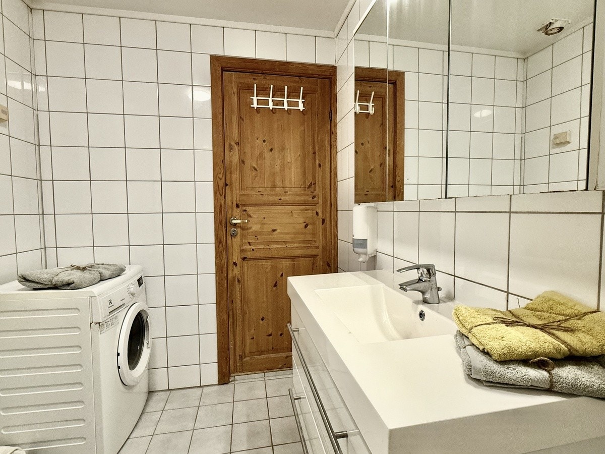Flislagt bad med varmekabler. Dusjkabinett og WC. Servant med skuffer og overskap med speil. Galleribilde
