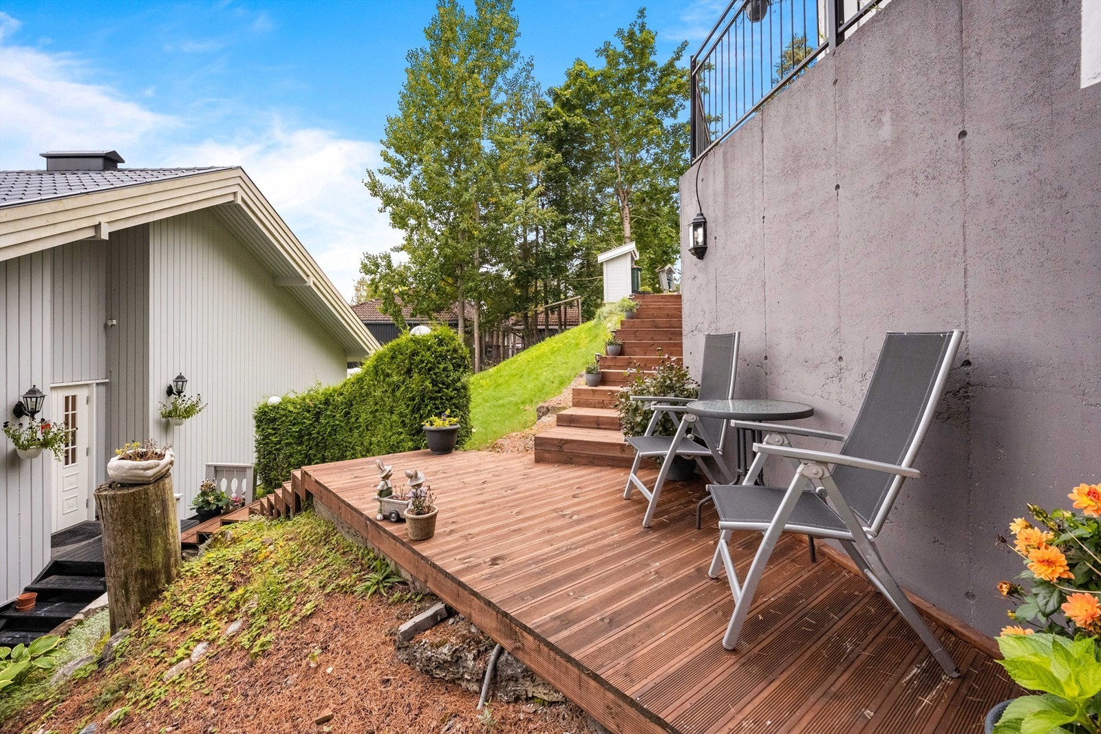 Tomten er pent opparbeidet med plenarealer, beplantning og trapper i terrenget. Galleribilde