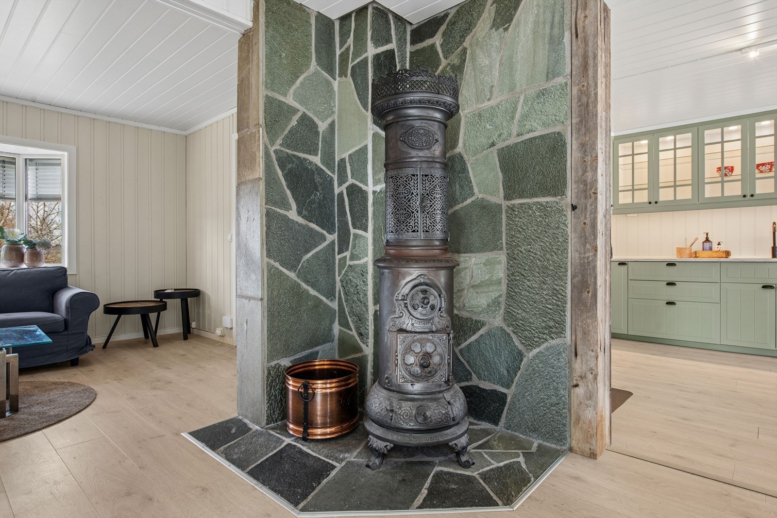 En klassisk vedovn sentralt plassert mellom stue og kjøkken gir både varme og sjarm. Galleribilde