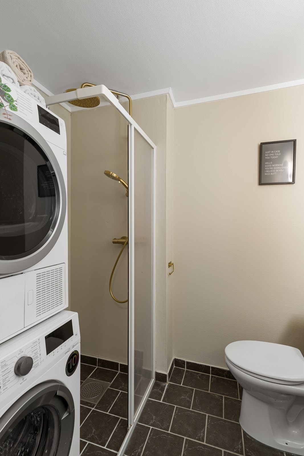 Badet/vaskerommet har flislagt gulv, dusj med aluminium og pleksiglass, samt opplegg for vaskemaskin med stoppekran. Galleribilde